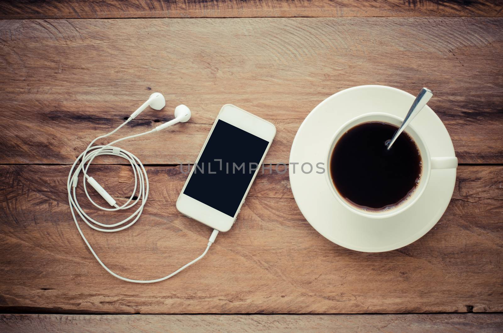 top view image of smartphone with blank screen headphones coffee cup and costome on wooden floor by photobyphotoboy