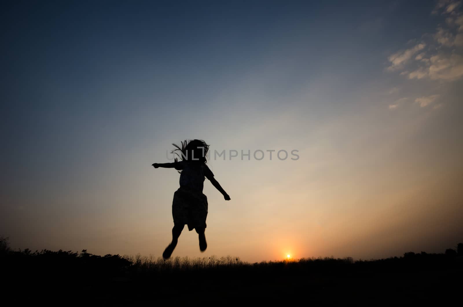 Silhouette of a girl gesture happy with the golden light of the sunset,