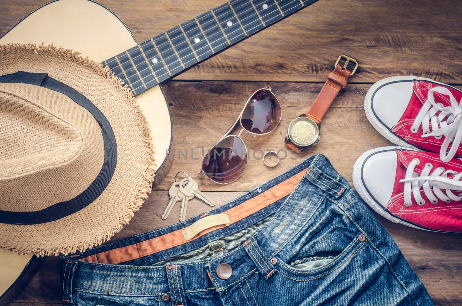 Guitar, sneakers, sunglasses, hats, watches, apparel accessories for men on the wooden floor.