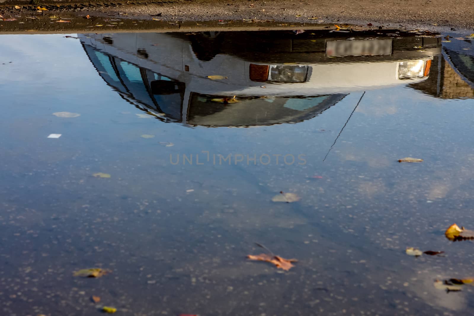 Car reflected in the water on the road, Latvia.