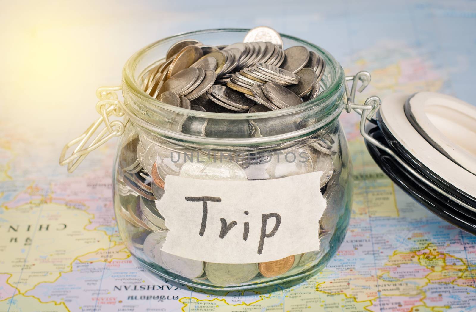 Target for travel - concept saving money in a glass and word "trip" on map