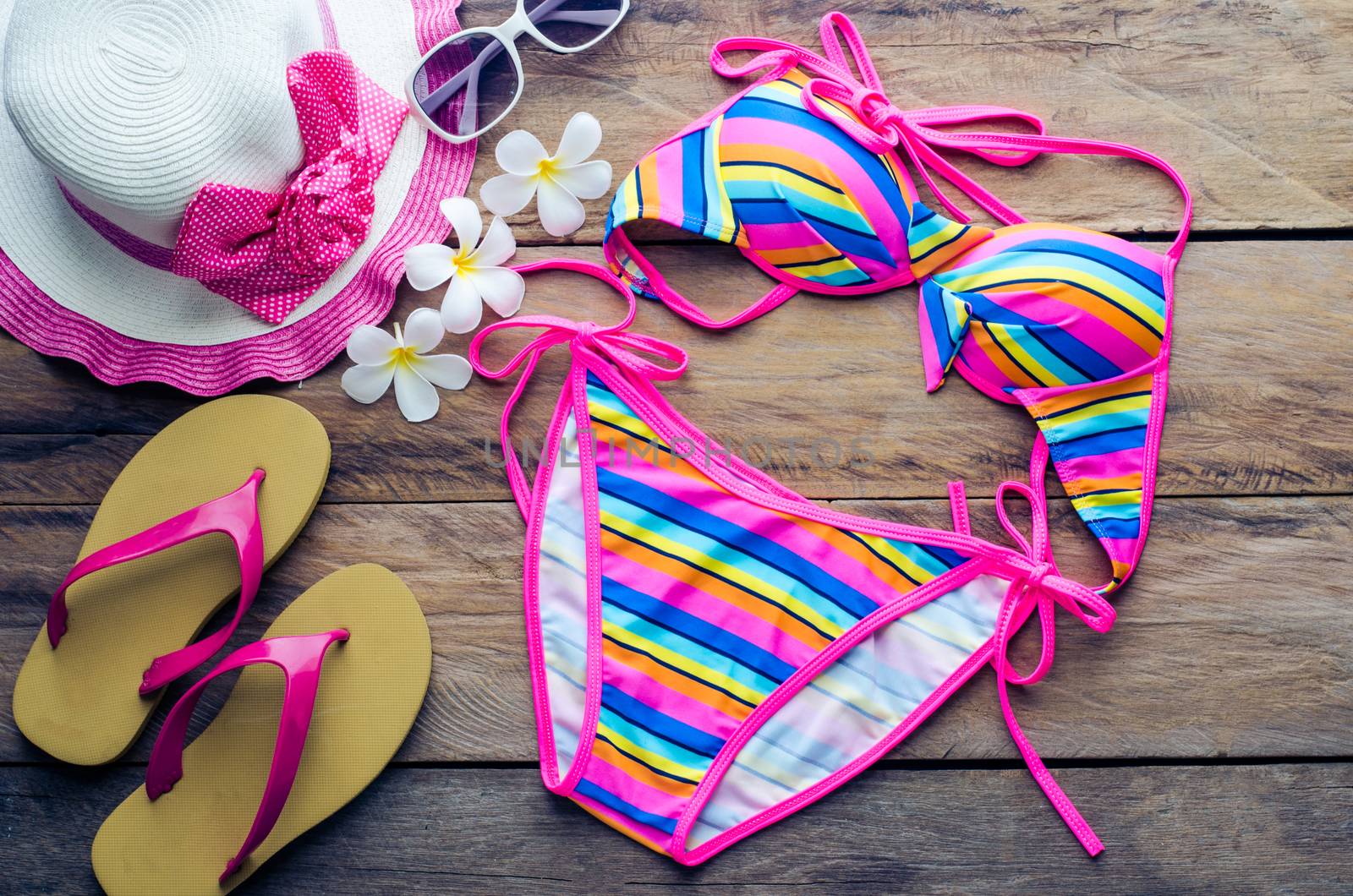 Beauty colorful bikini and accessories on wooden floor