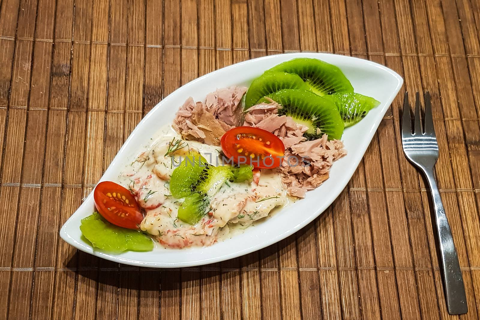 Healthy low-carbohydrate food in small bowl, lunch with tomatoes, tuna, kiwi, shrimp homemade sugar-free sauce.