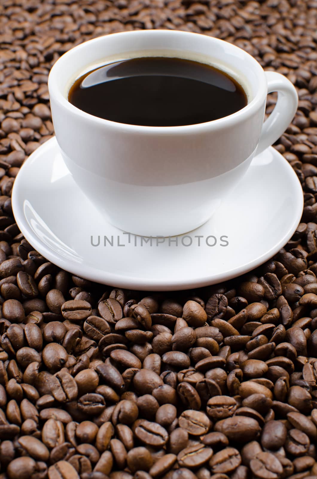 White cup with black coffee on the coffee beans.