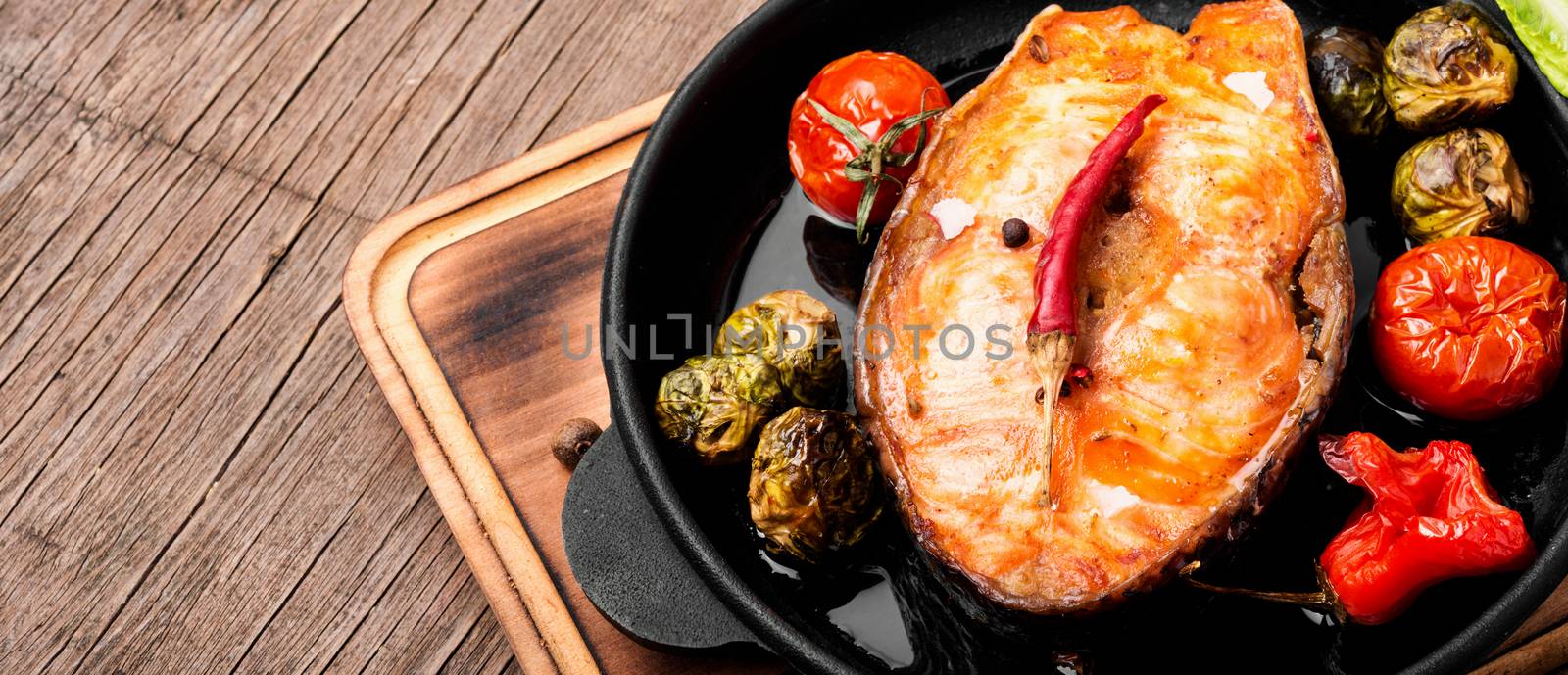 Baked salmon with tomato, pepper and cabbage.Fish steak with vegetable garnish.Long banner