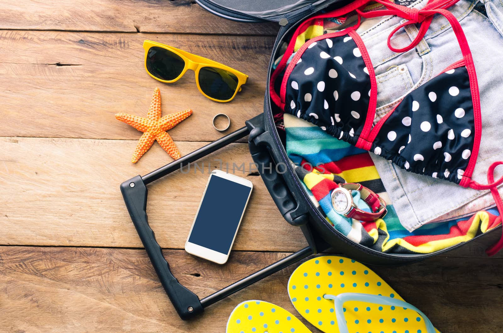Clothing traveler's , wallet, smart phone devices, on a wooden floor in the luggage ready to travel.