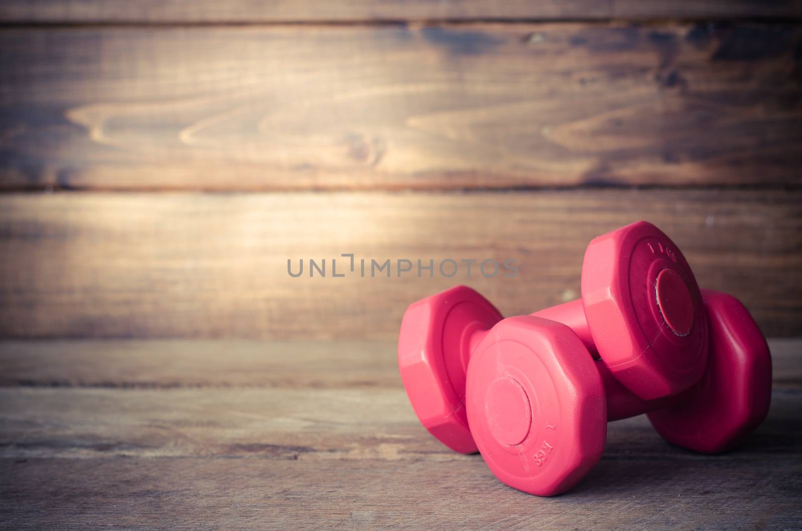 Double red dumbbells 1 kg on wood background.
