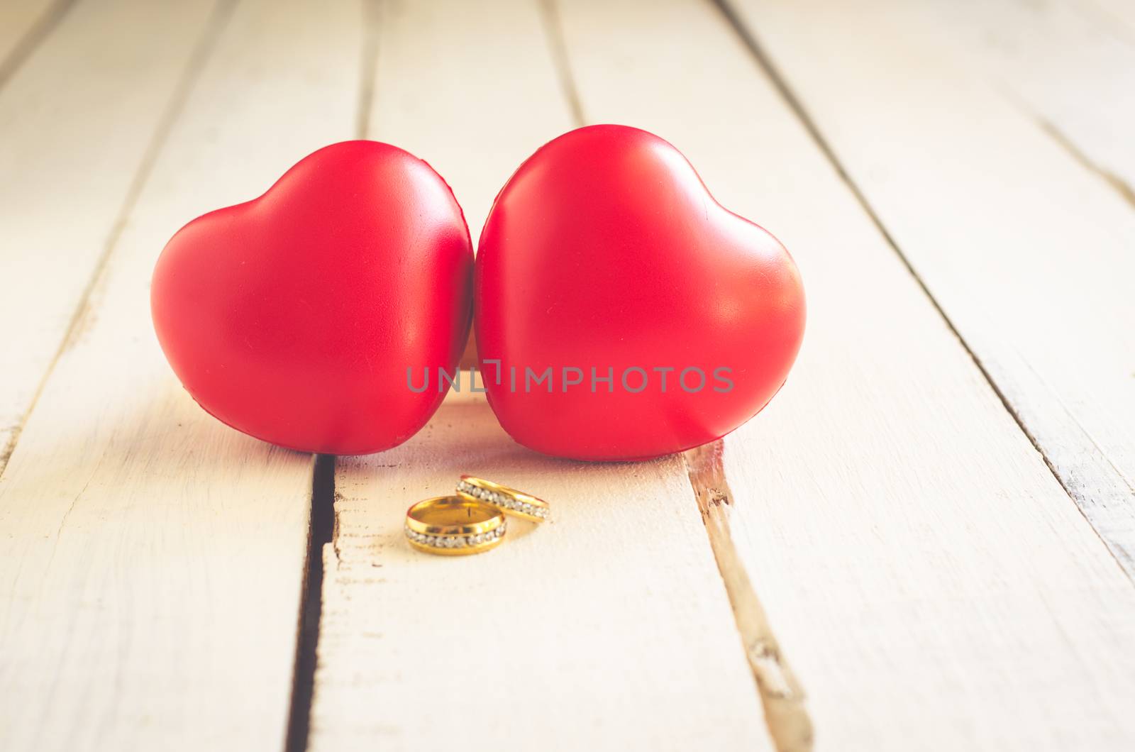 Valentine background with heart wedding rings resting on the wooden floor.