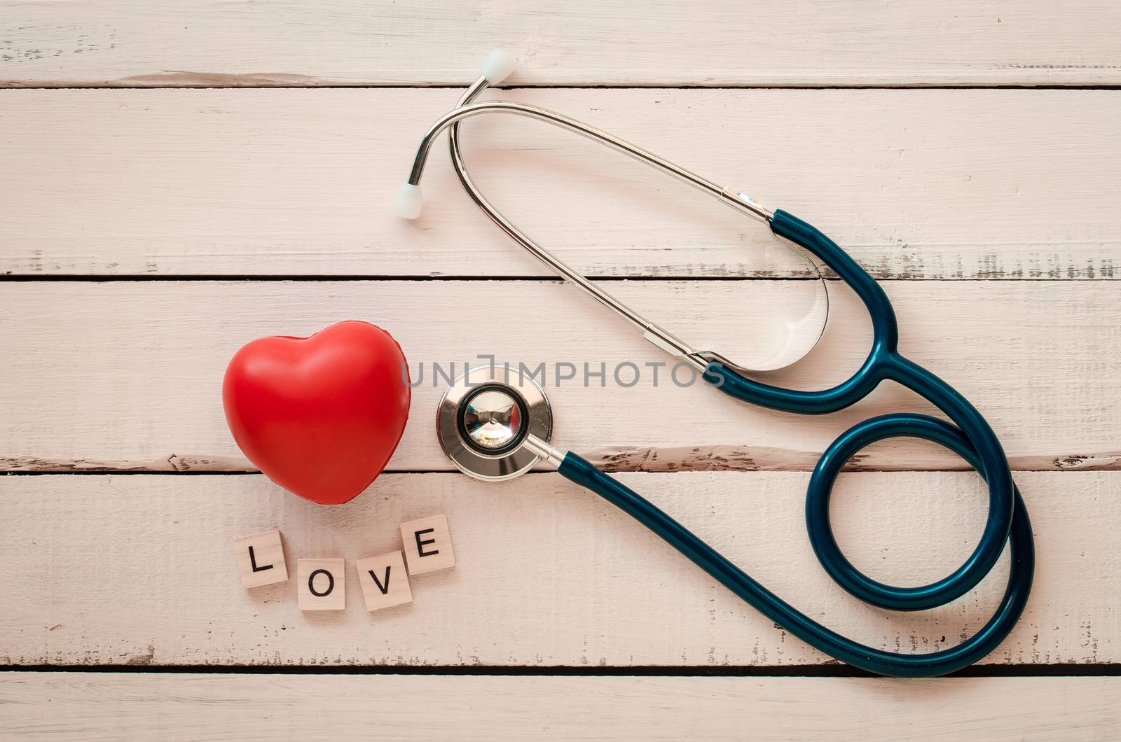 stethoscope heart and the word "love"on wooden floor