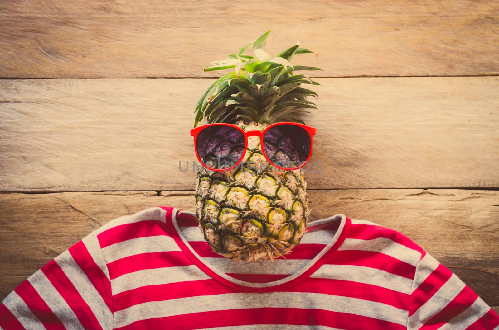 Pineapple sunglasses resting on the wooden floor concept travel.