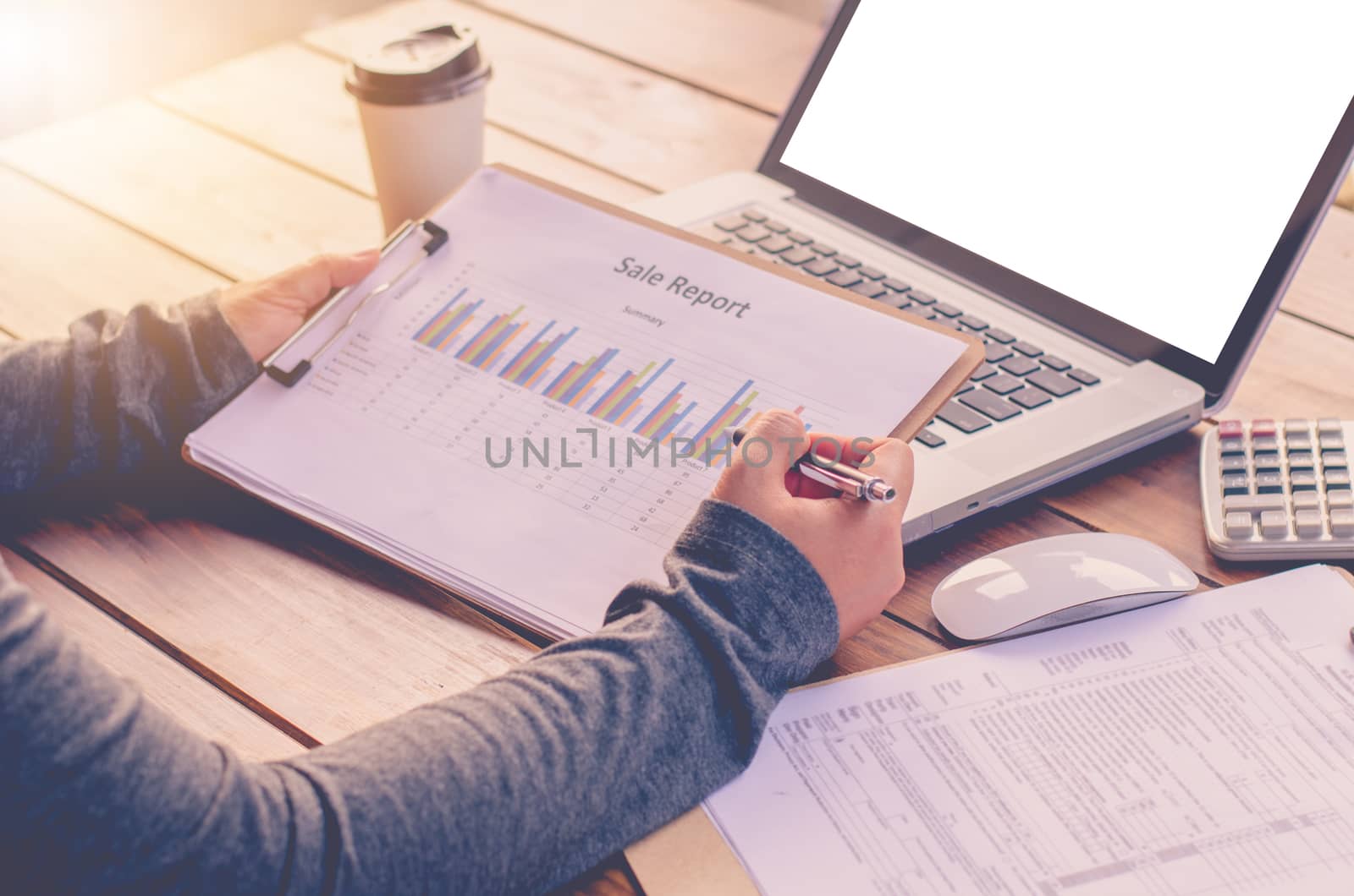 Businessman holding paperwork on the table and analyzing investment chart working in office. Business work concept