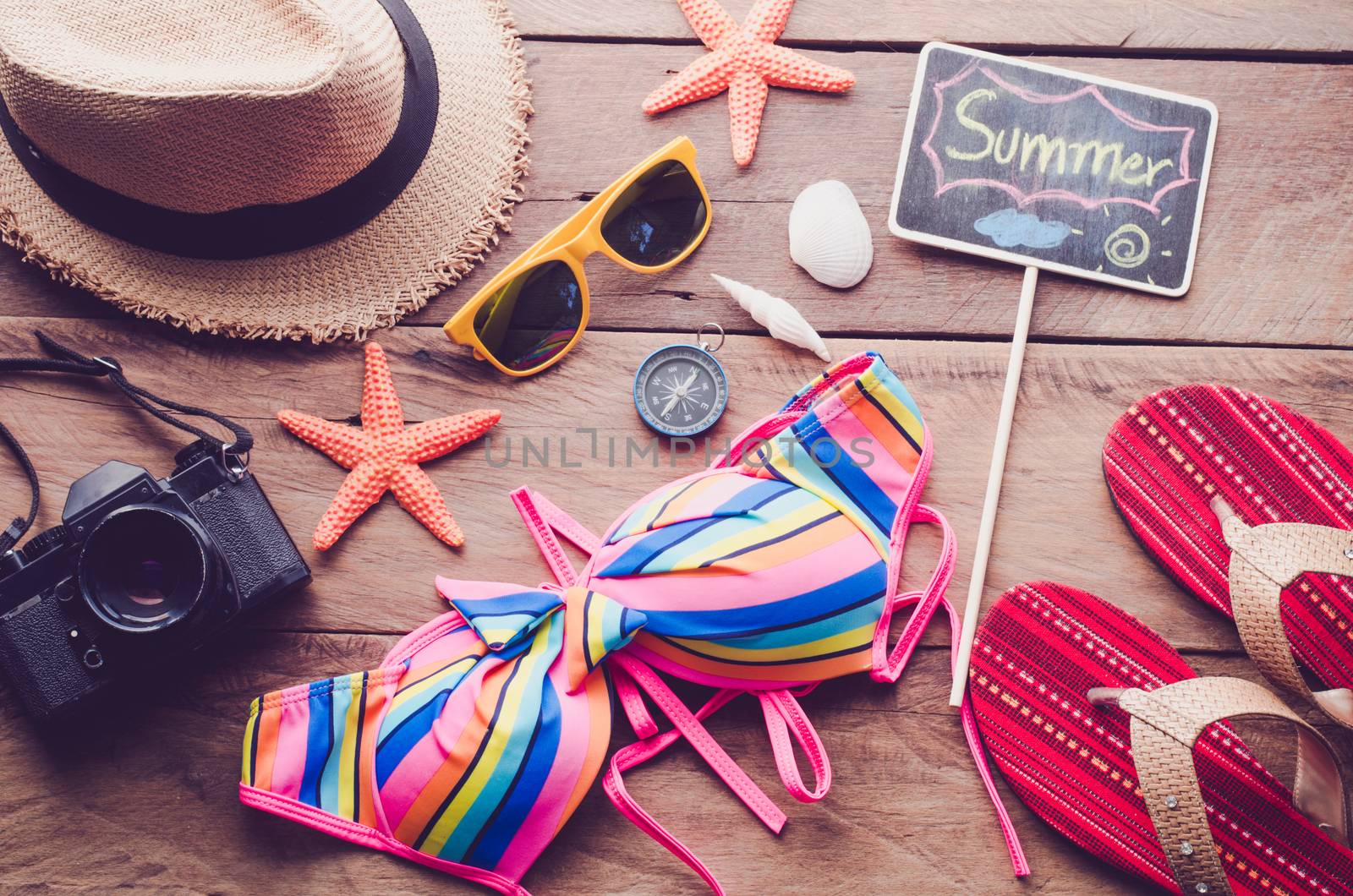 Sea travel accessories colorful bikini and accessories sandals. Placed on wooden and word 'SUMMER" on blackboard