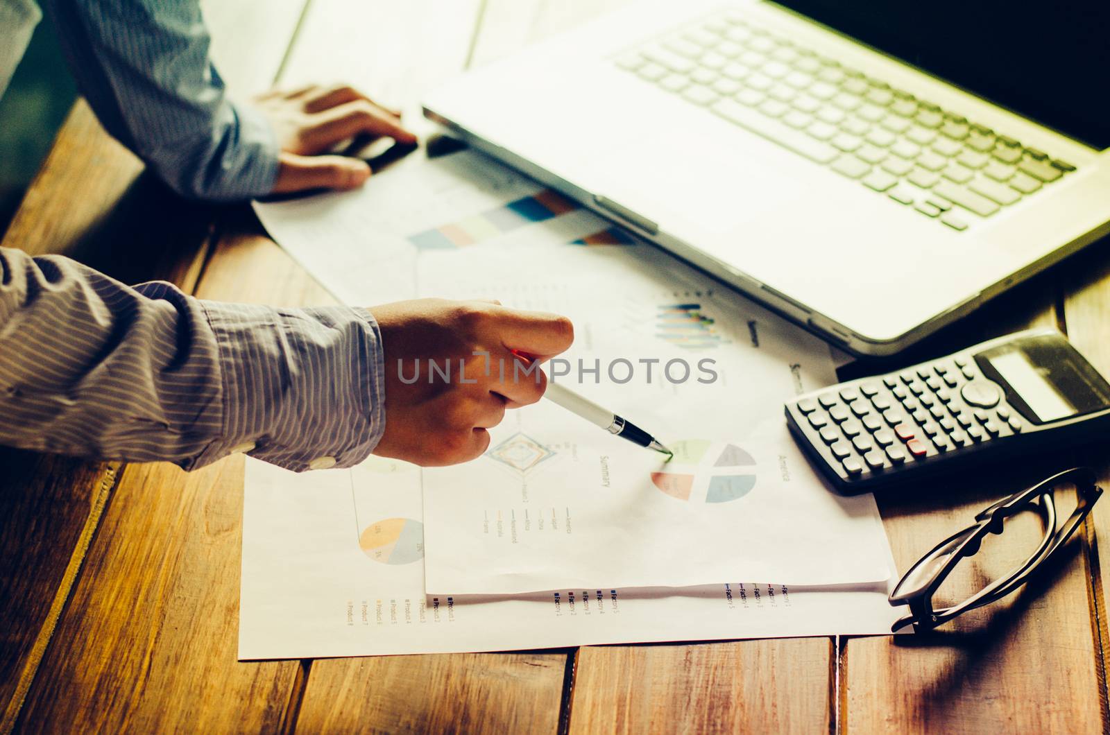 Businessman holding paperwork on the table and analyzing investment chart working in office. Business work concept. 