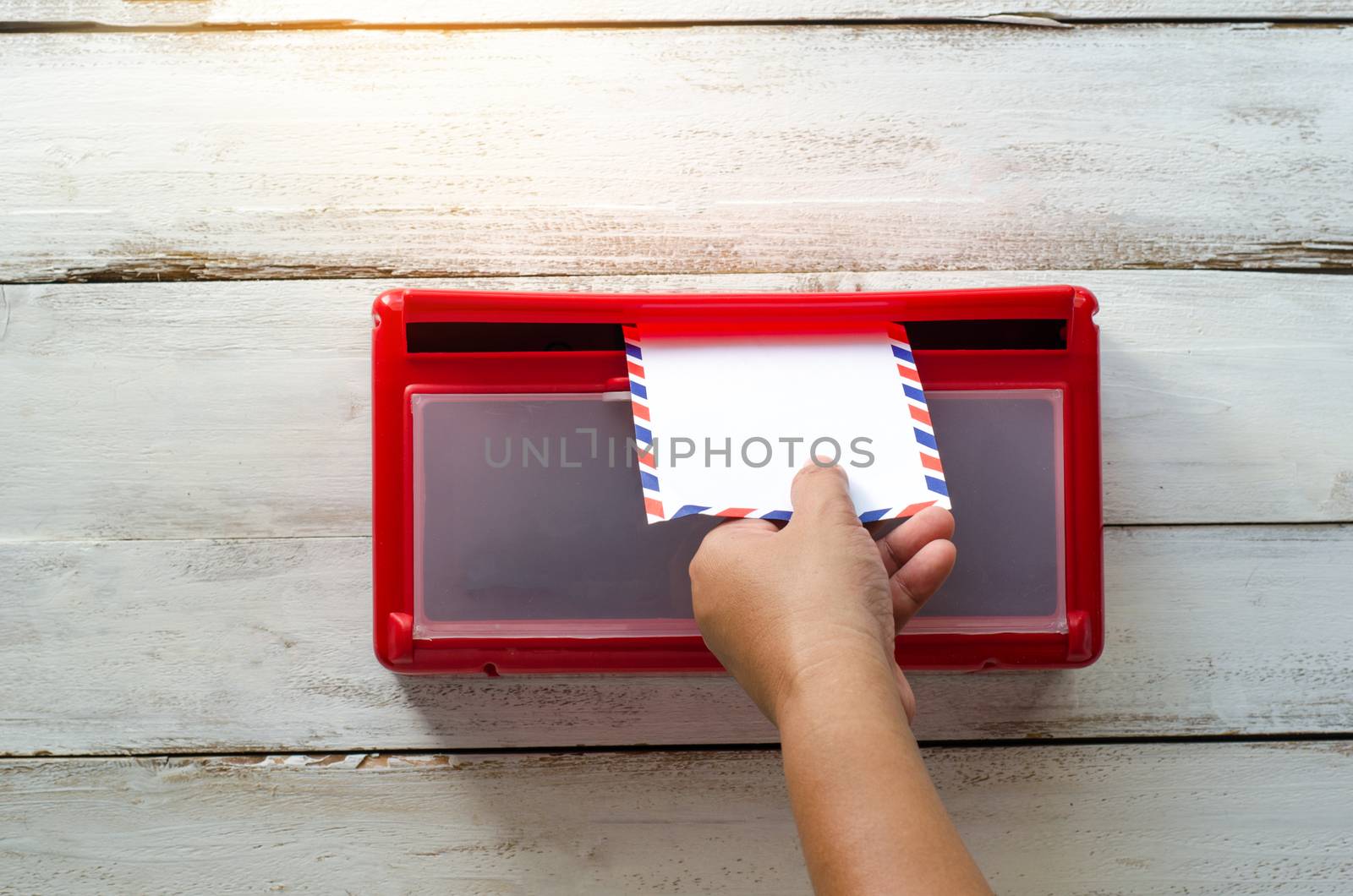 Hands are picking up the envelope in the mailbox.