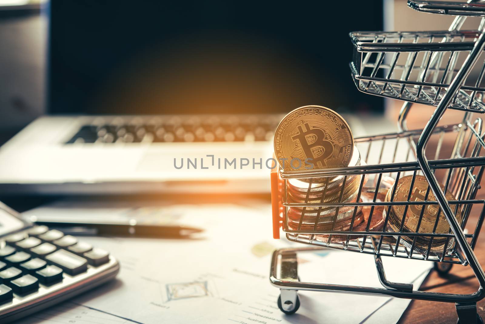 Bitcoin in mini shopping cart on table for work and laptop for work to shopping online concept 