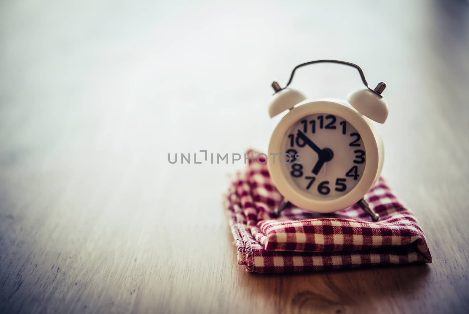 White alarm clock and handkerchief on white table