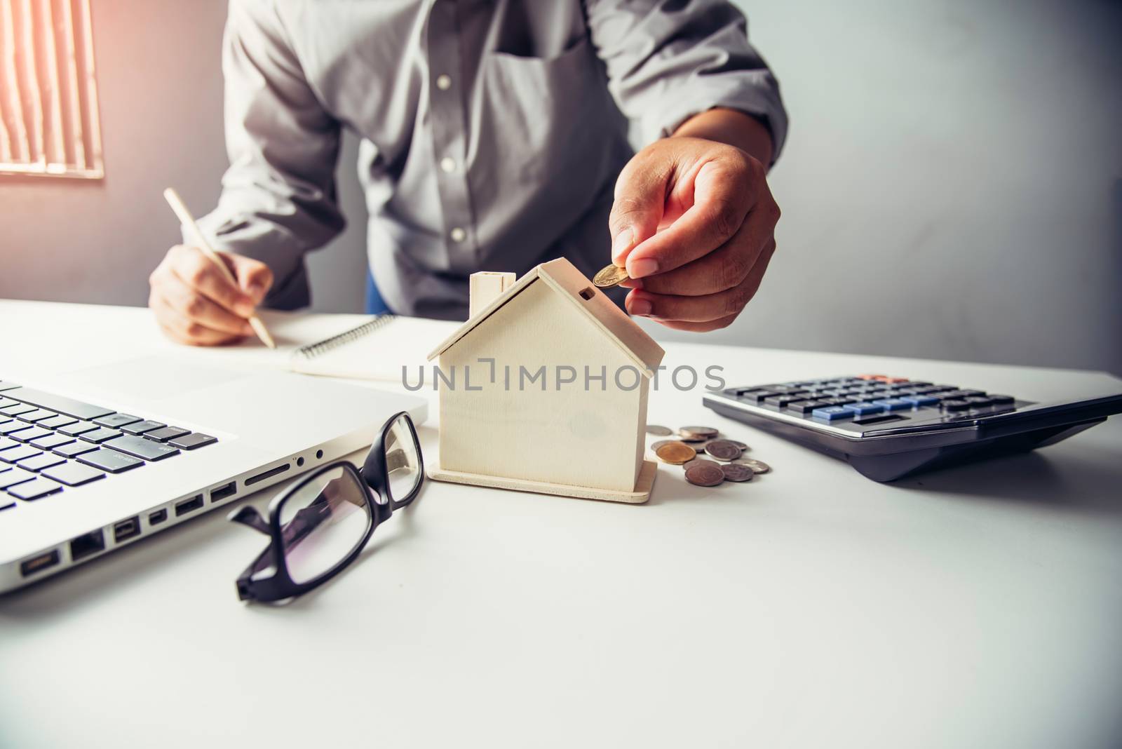  Hand business putting money coin  with wooden house,Property investment and house mortgage financial concept