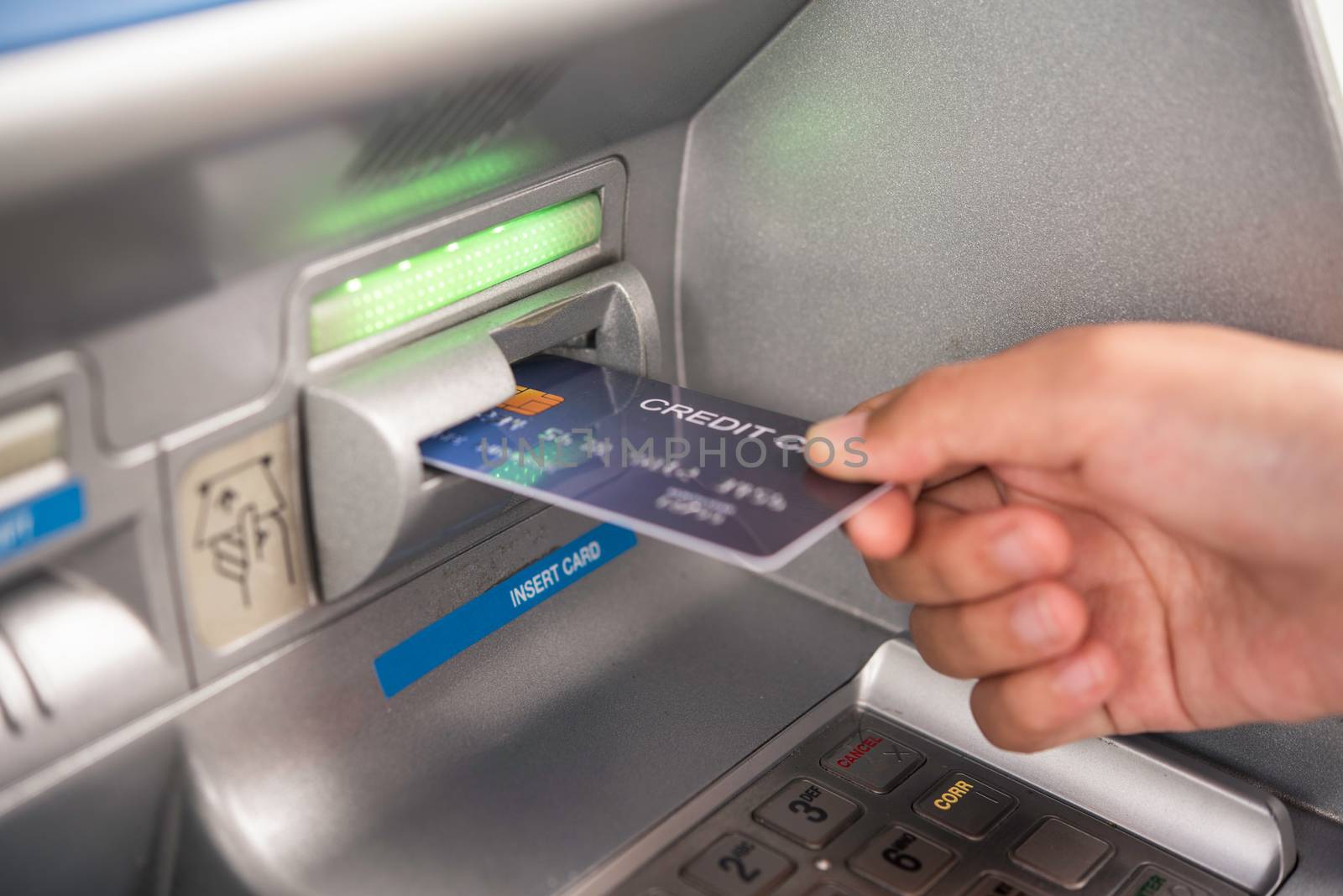 Hand inserting with a credit card into bank machine . Man using an atm machine with  credit card to withdraw money