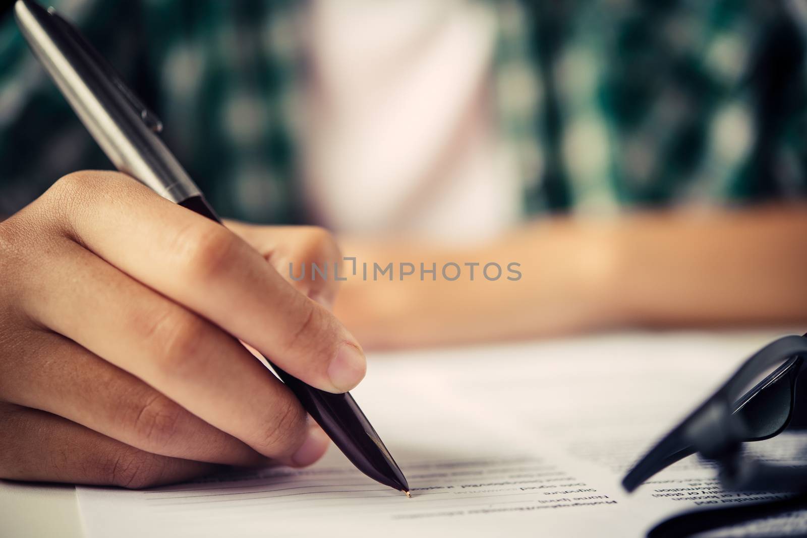 Close up of woman hands writing inon paper placed on wooden in office