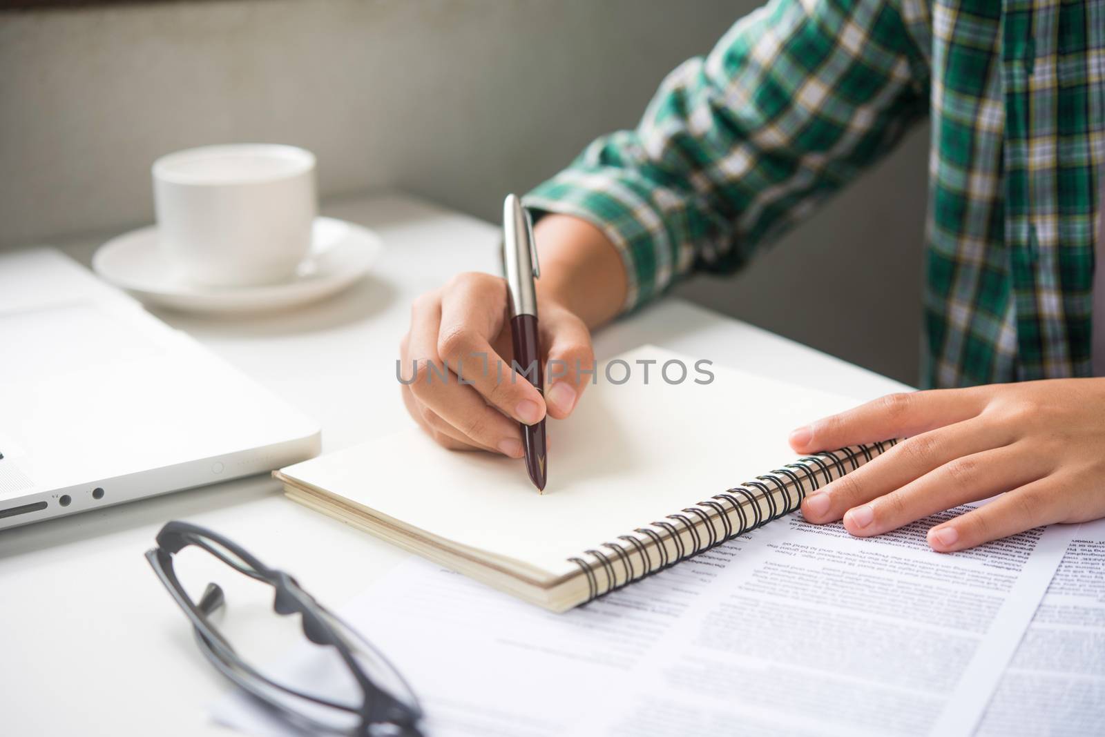 Close up of woman hands writing inon paper placed on wooden in office