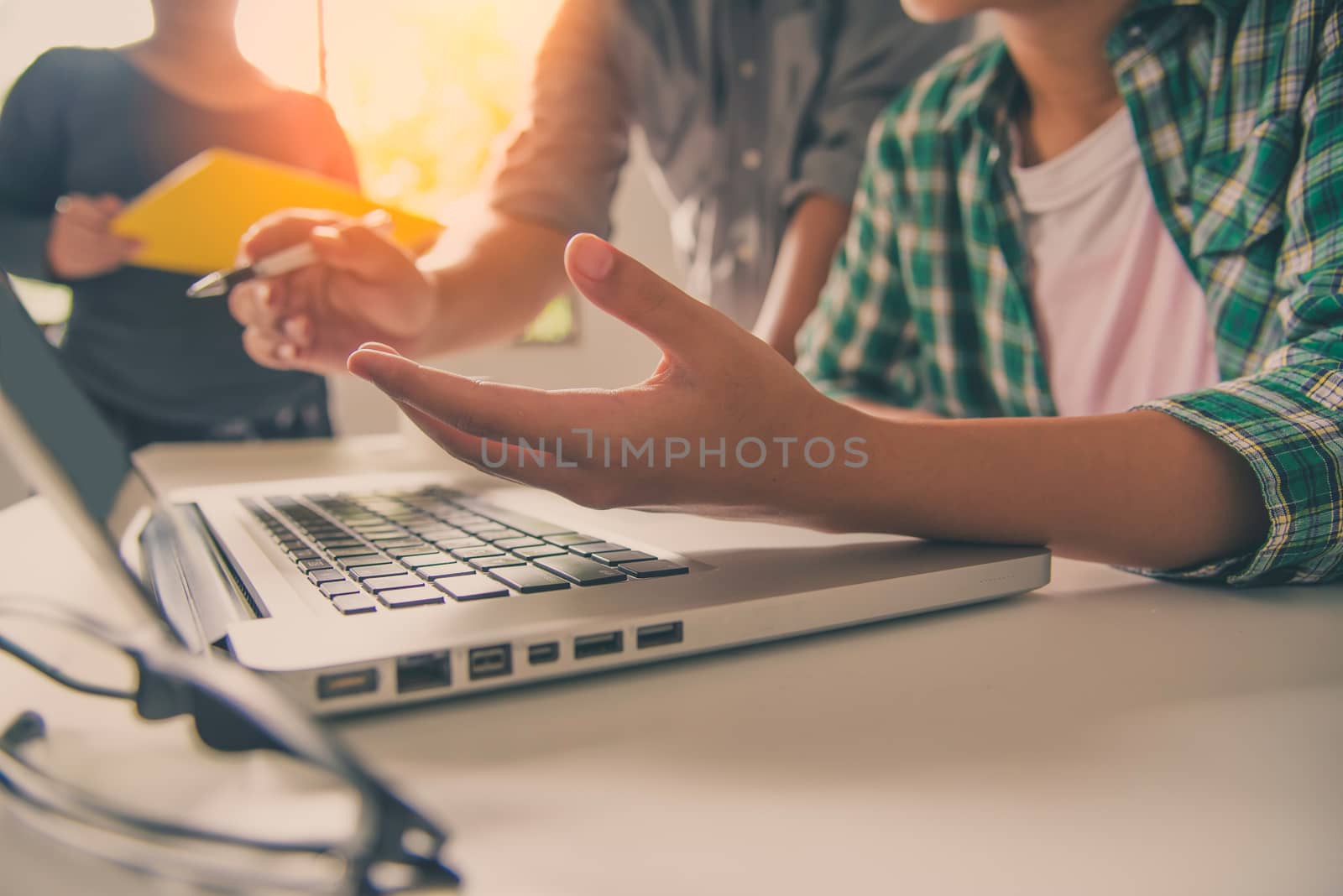 Business people work together to analyze problems, discuss business approaches with smartphone laptops, and office documents in sun glare effect