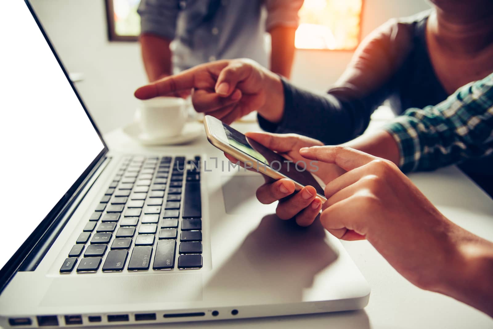 Business people work together to analyze problems, discuss business approaches with smartphone laptops, and office documents in sun glare effect