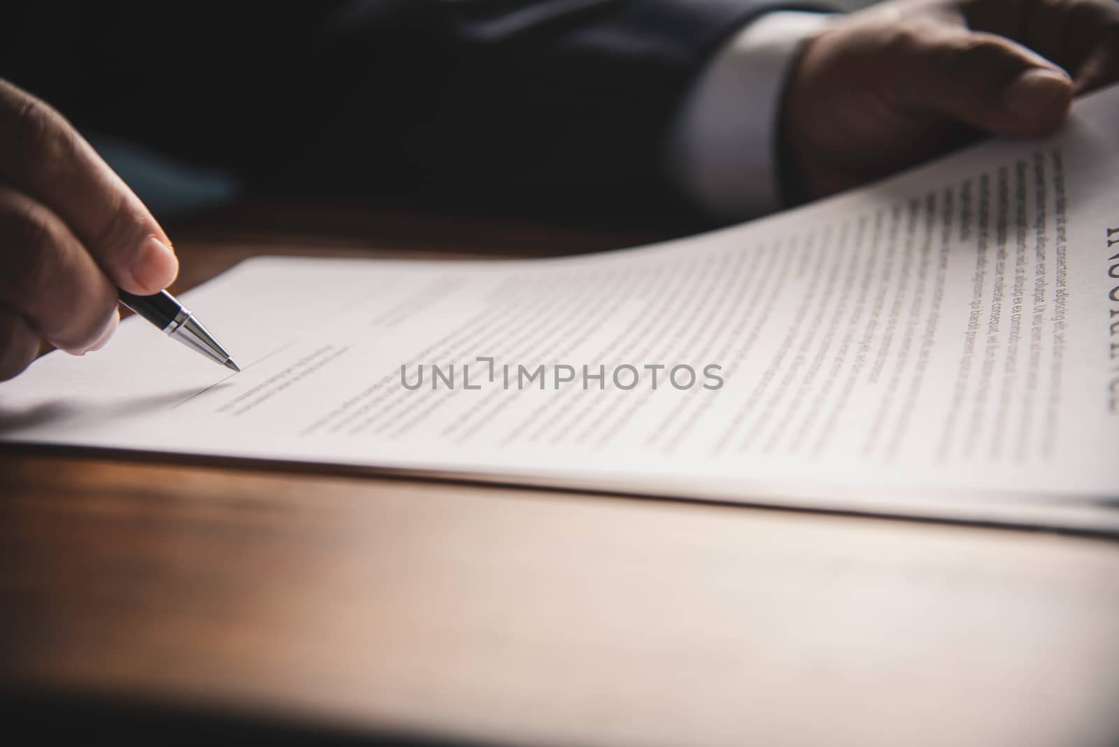 Hand holding pen signing contract in important documents.