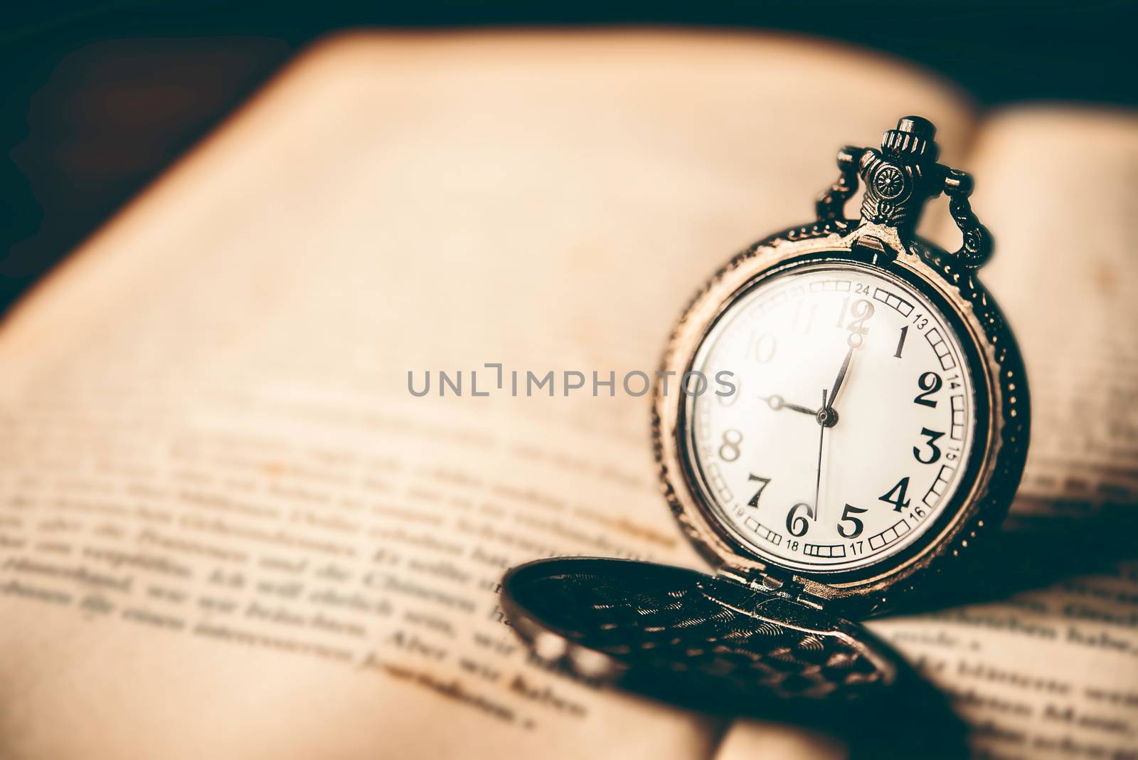 Antique clock placed on the book - vintage style.