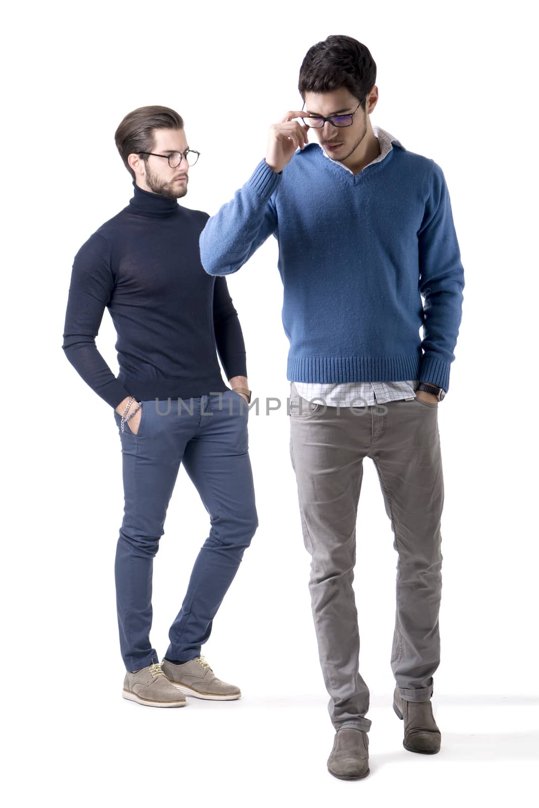 Two good-looking young men with eye-glasses in stylish clothes. Full figure studio shot, isolated on white