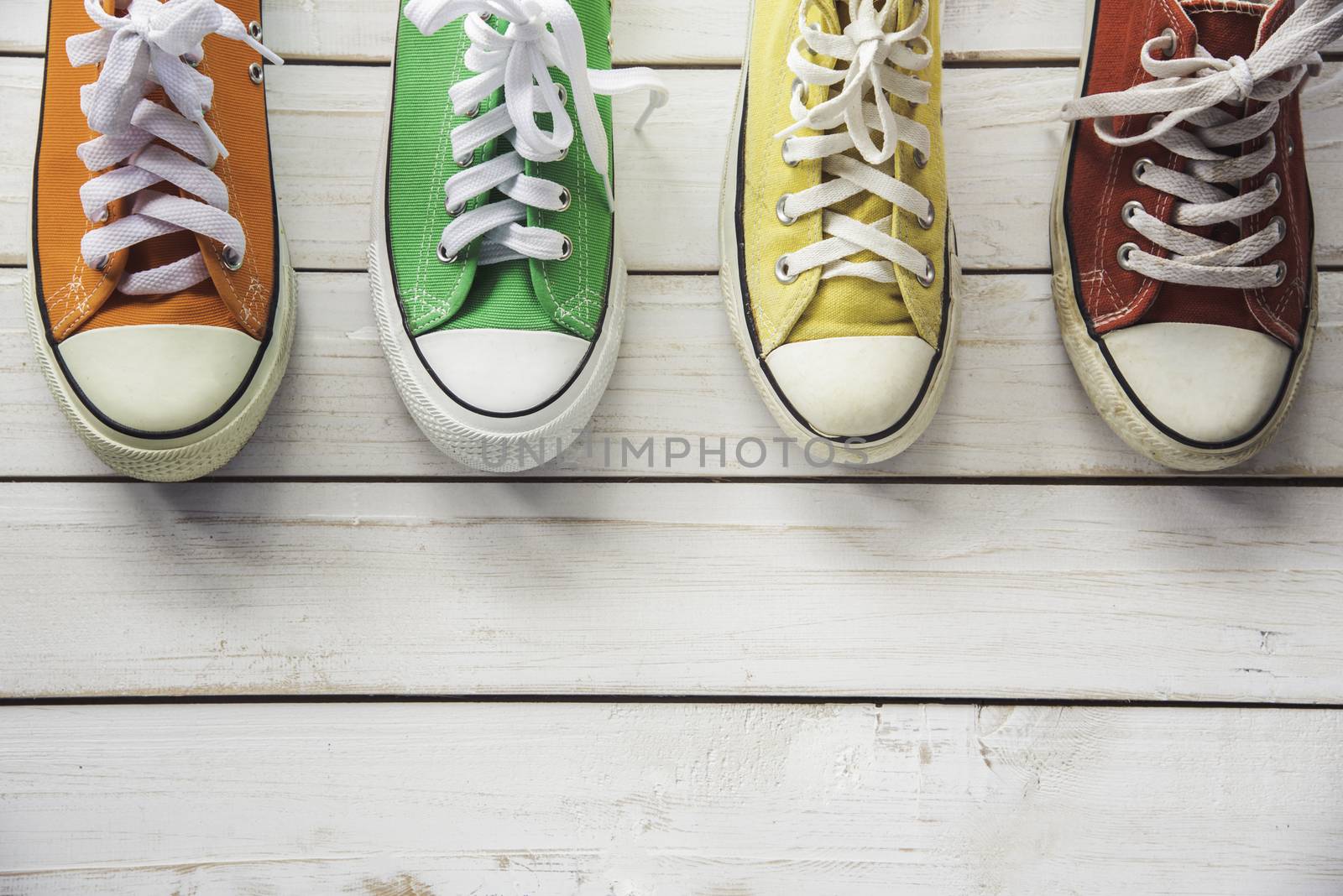 Sports shoes, work shoes, put on a white wooden floor - a living concept.