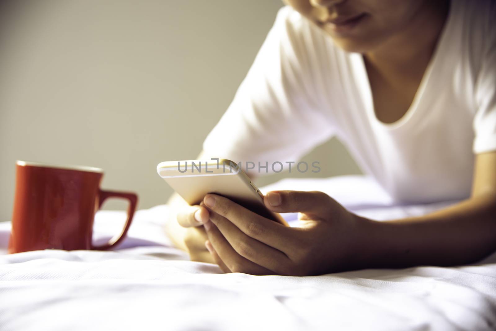teen playing phone on the bed.