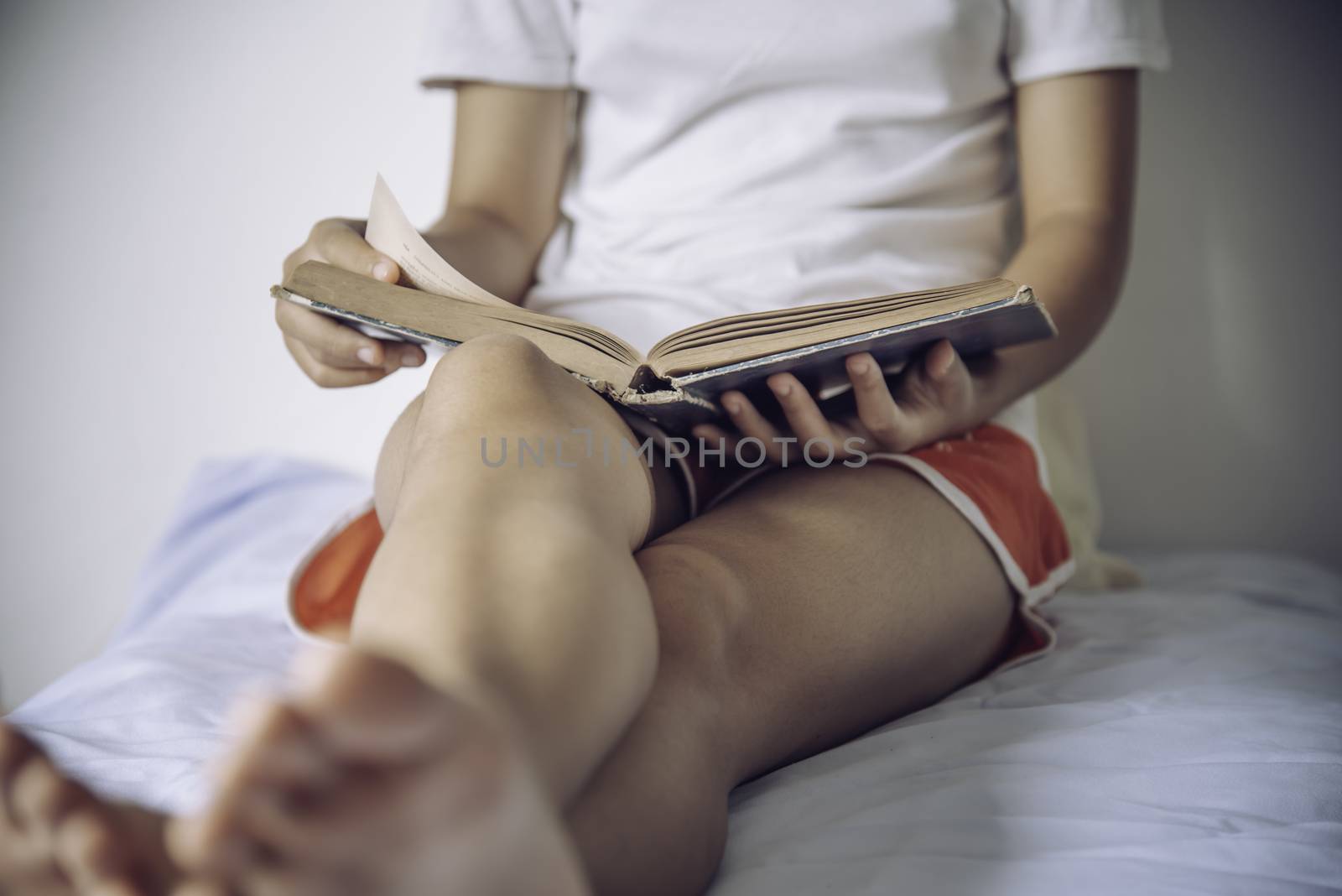 Teens read books on the bed in the bedroom.