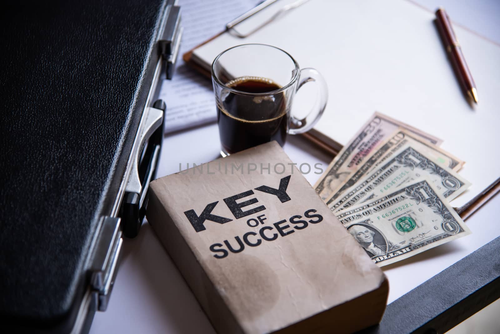 Black coffee and dollar is placed on a desk with office equipment and placed.