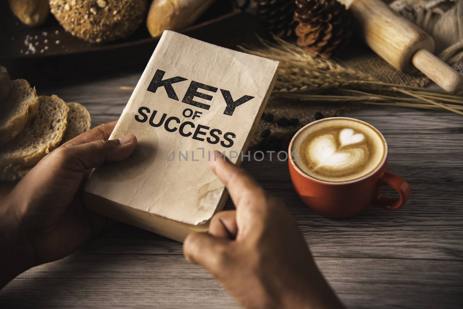 Hand holding a cup of coffee and reading a book key of success - concept lifestyle