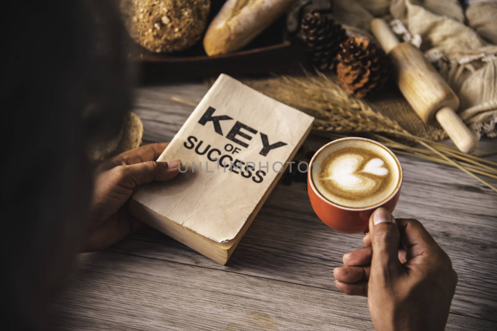 Hand holding a cup of coffee and reading a book key of success - by photobyphotoboy