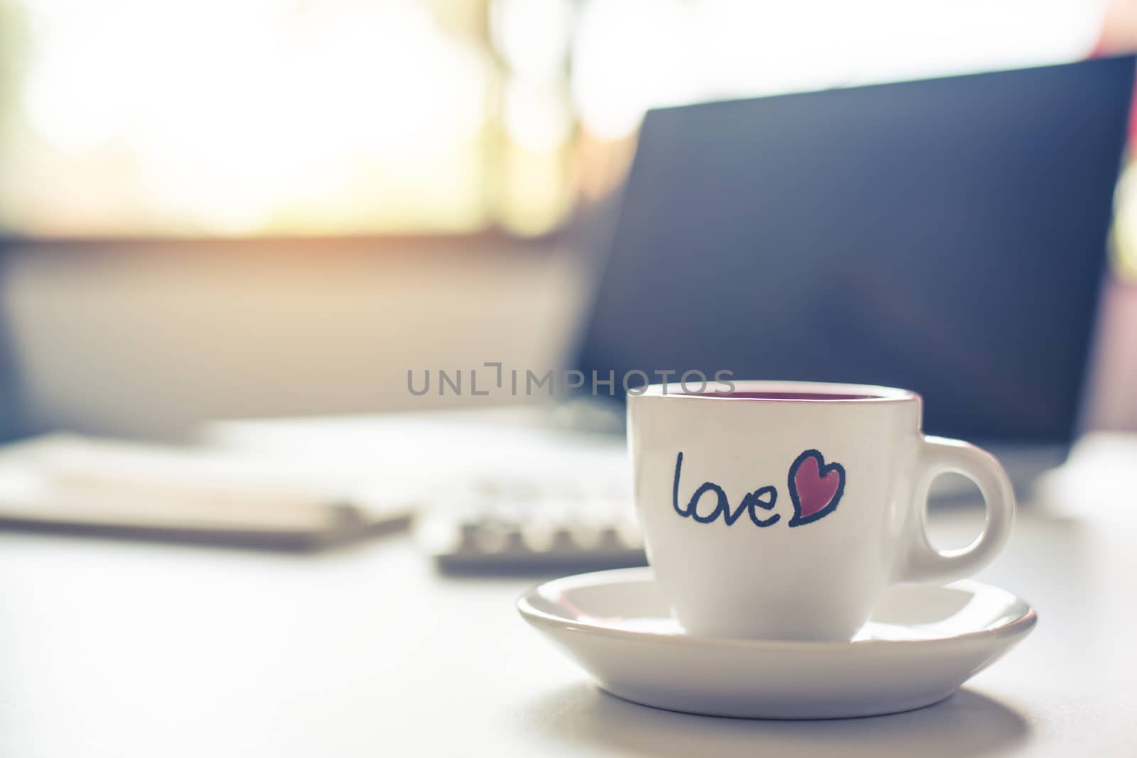 Coffee cup with "love" is placed on the desk.