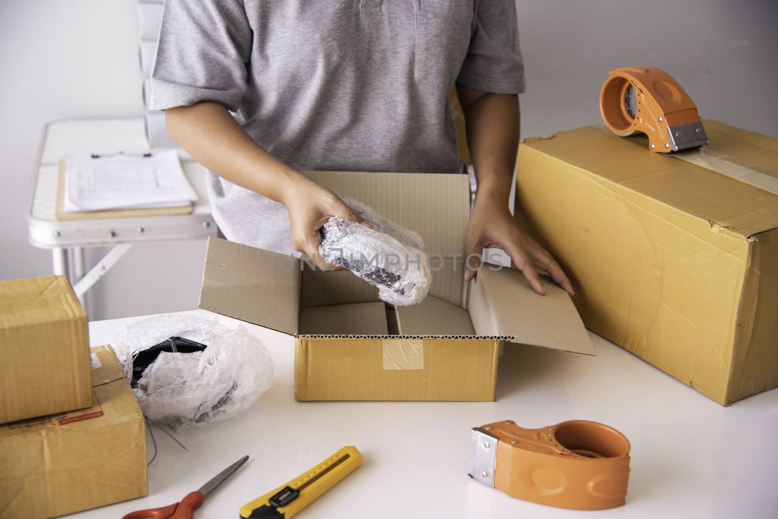 The staff is using the tape to pack the package goods to the customer.