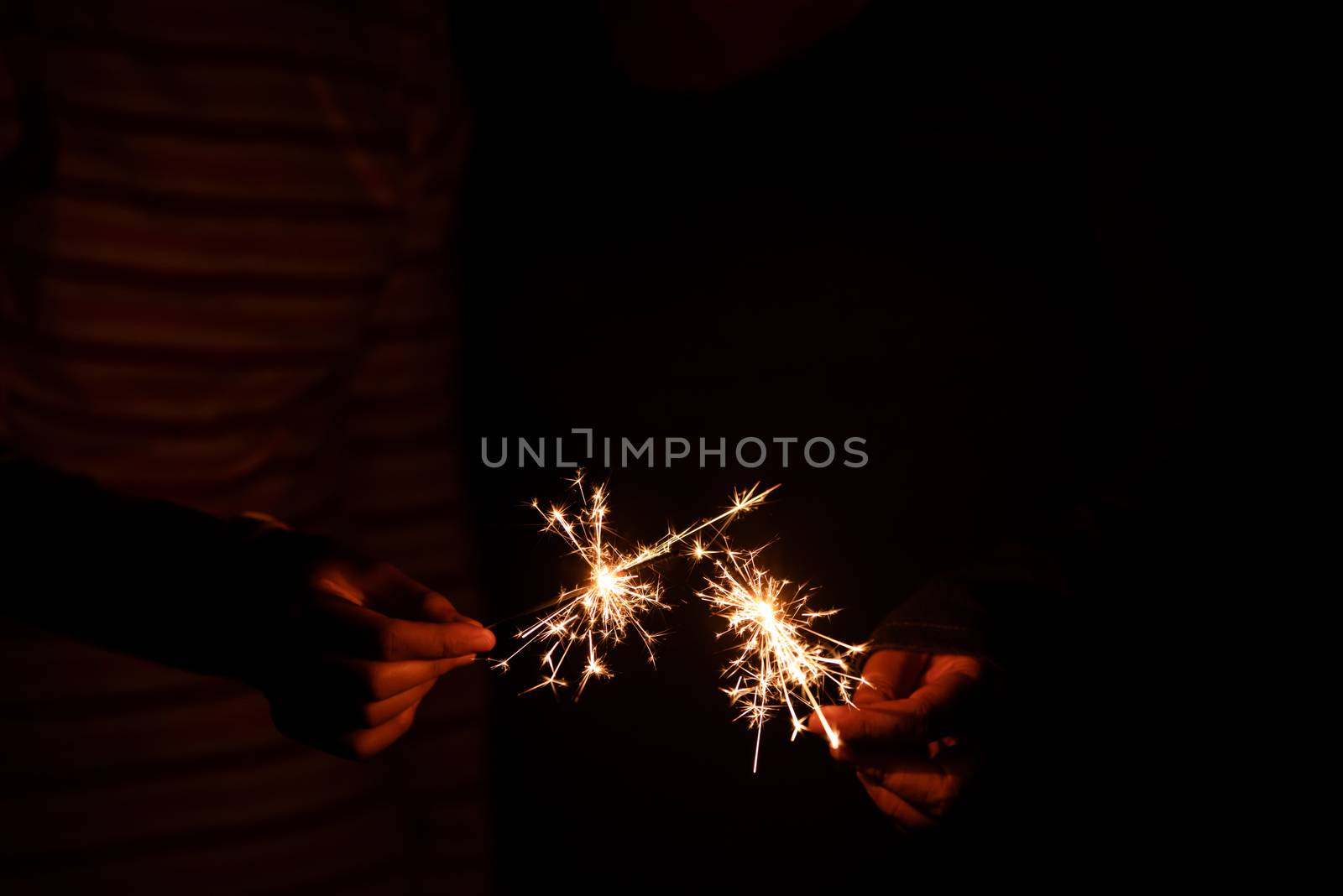 hand holding a sparkler at night during the festive season