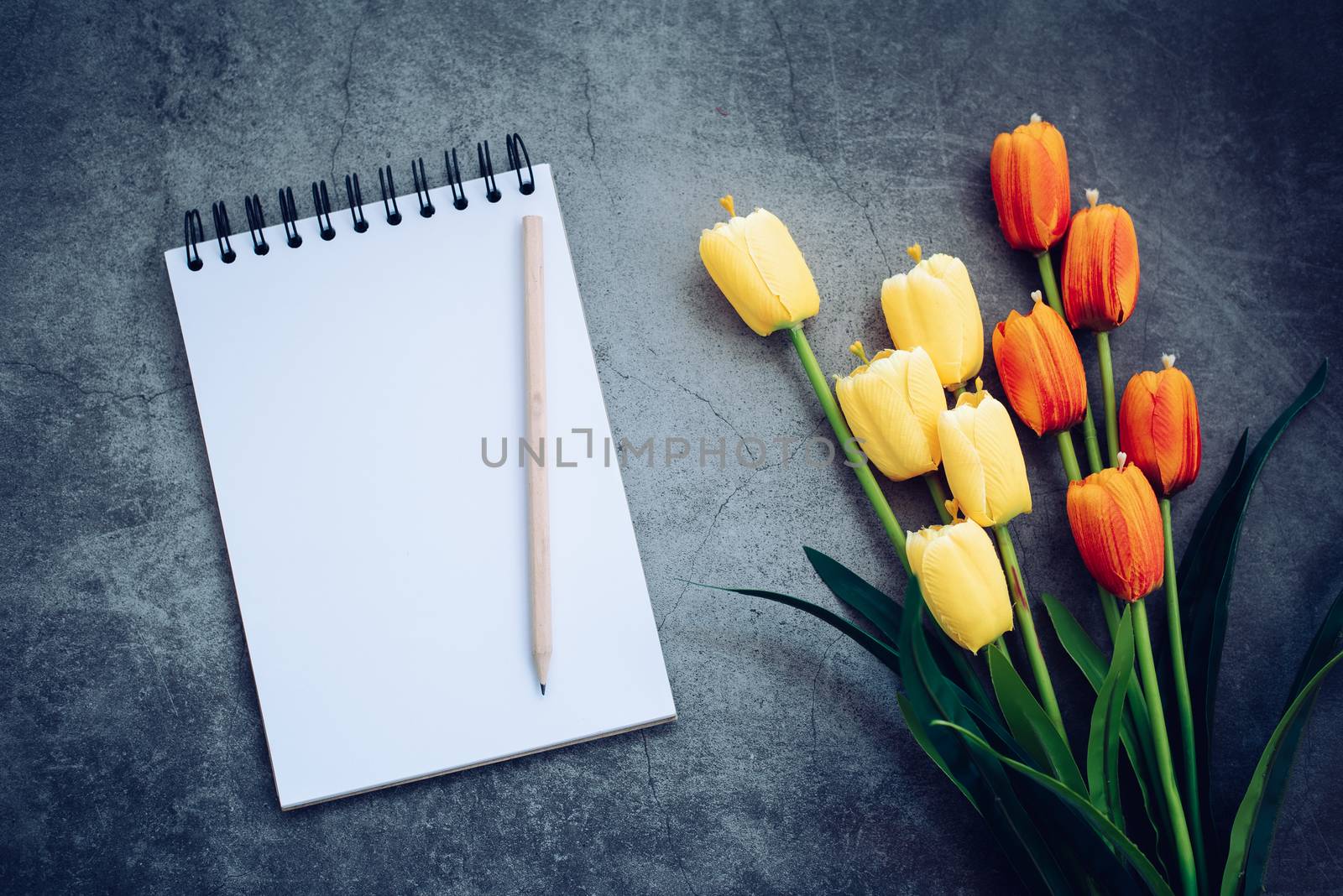 notebook ,pencil and flower on black background