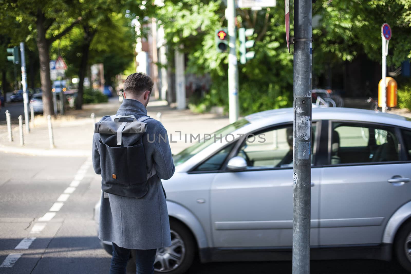 Young man pedestrian with smartphone standing on crosswalk by Vanzyst