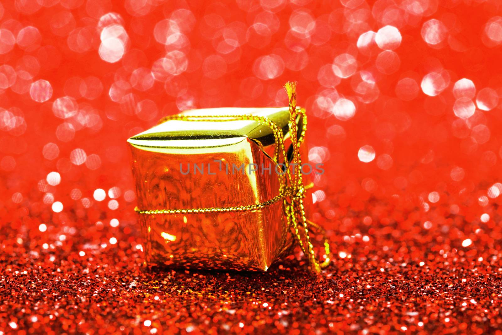 Decorative golden box with holiday gift on shiny glitter background