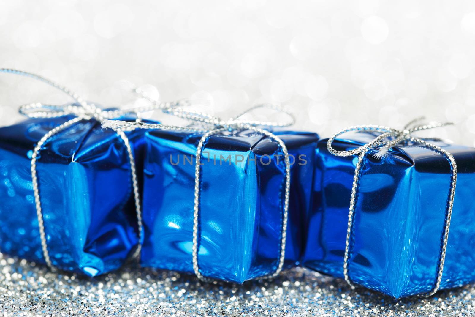 Small boxes with decorative holiday gifts on silver bokeh background