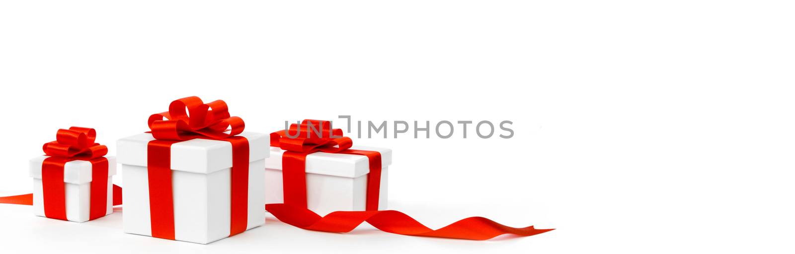 White gift boxes with red ribbon bows isolated on white background close-up