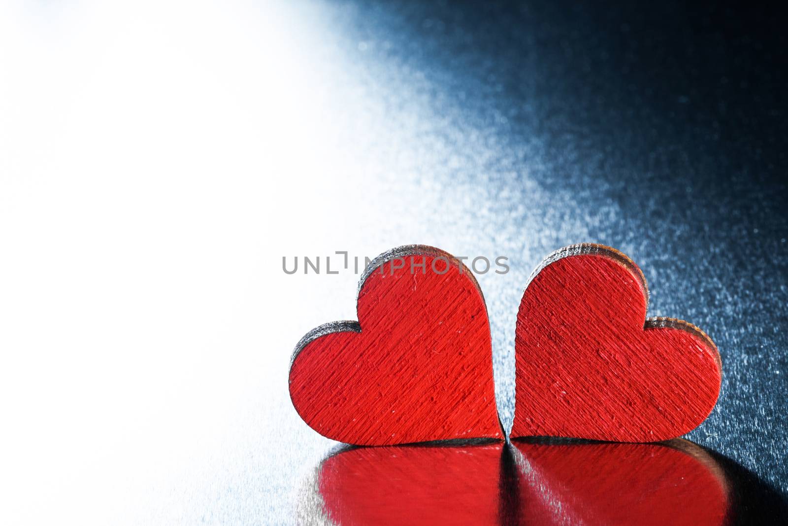 Two wooden red painted Valentine day hearts on metal background
