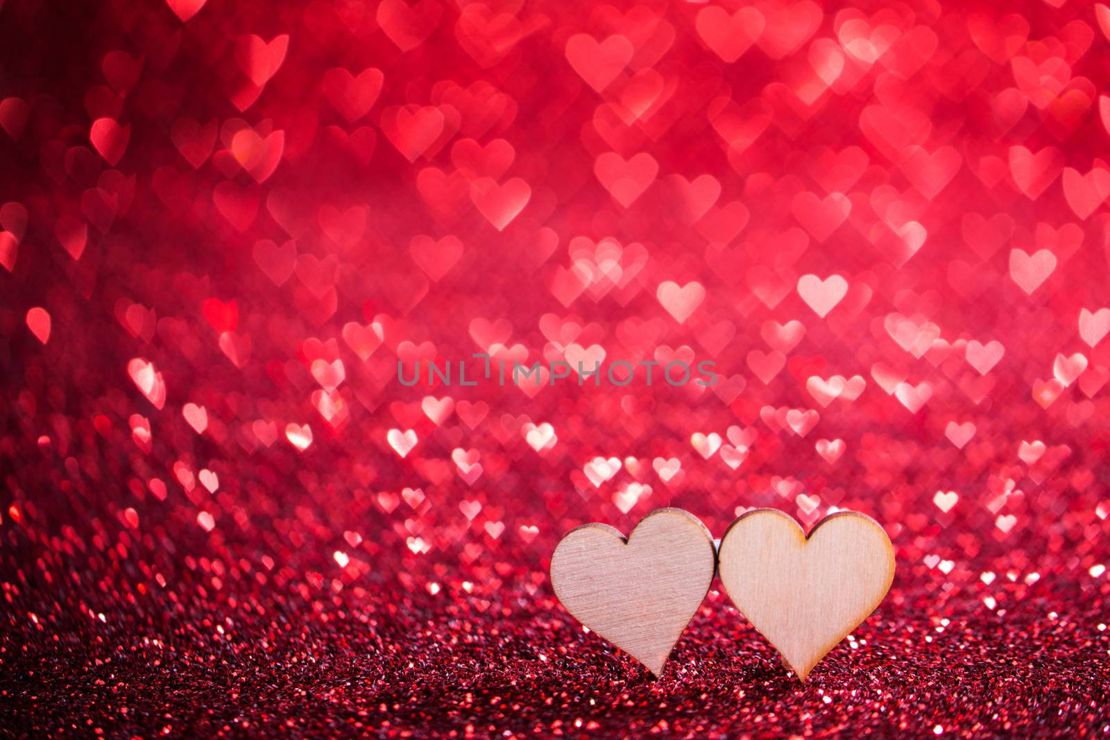 Two wooden hearts on red glowing bokeh hearts background for Valentines day