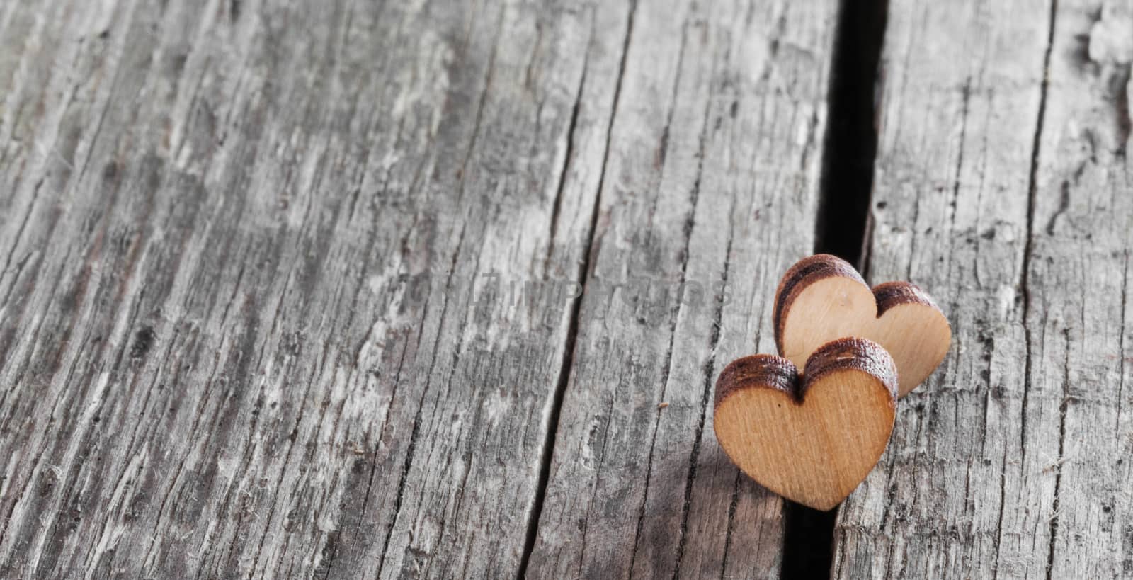 Two small wooden hearts on old cracked wood background