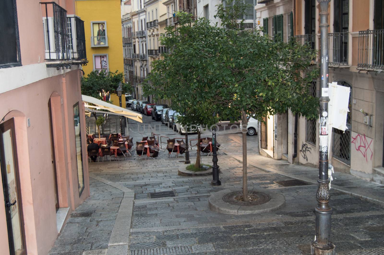 Traditional outdoor cafe on a narrow cobbled street after rain in Cagliari, Italy, 09 October 2018, SELECTIVE FOCUS.