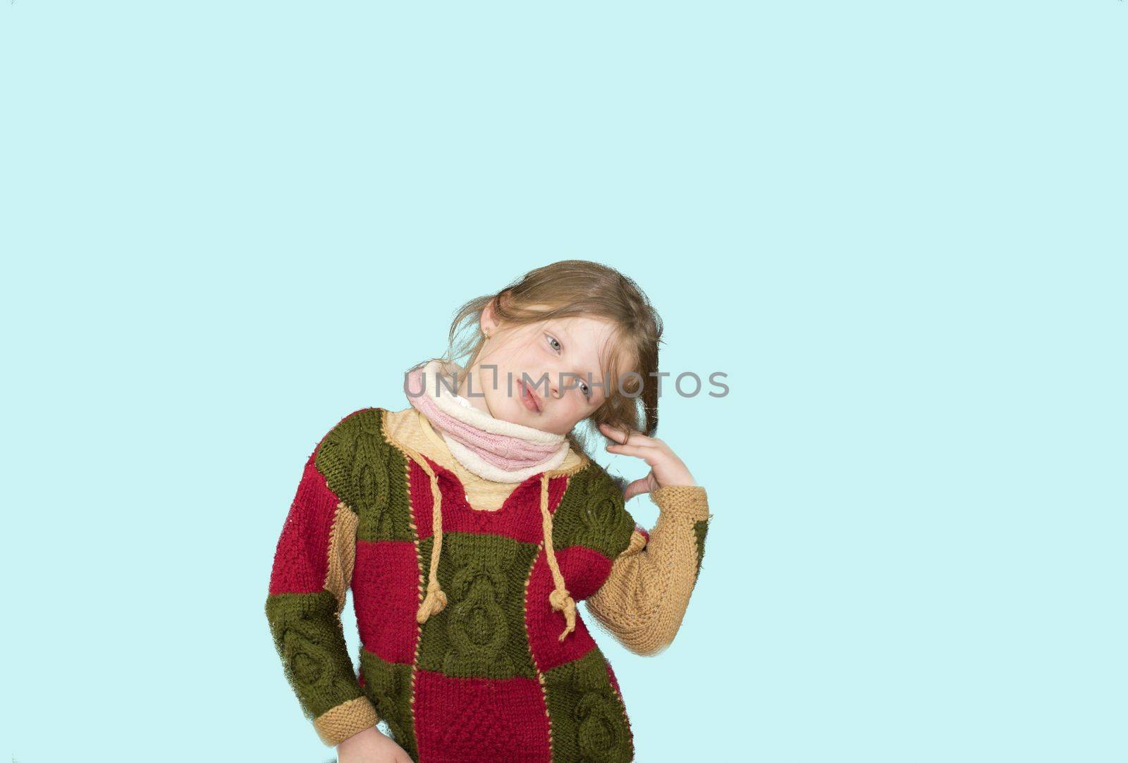 Little girl on colourful background. Copy space. Young girl is wearing sweater. Soft blue background.