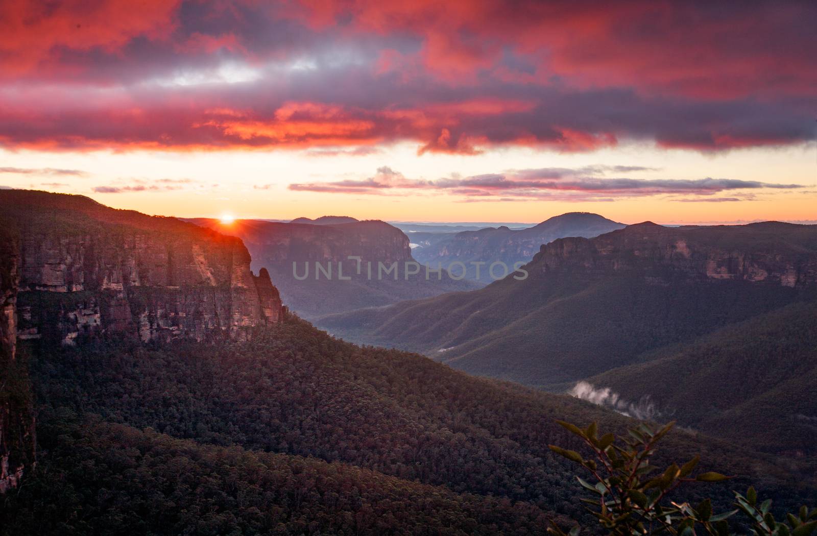 Rich red sunrise blanketing the skies above the Grose Valley as viewed from the cliffs at Govetts Leap, Blue Mountains Australia