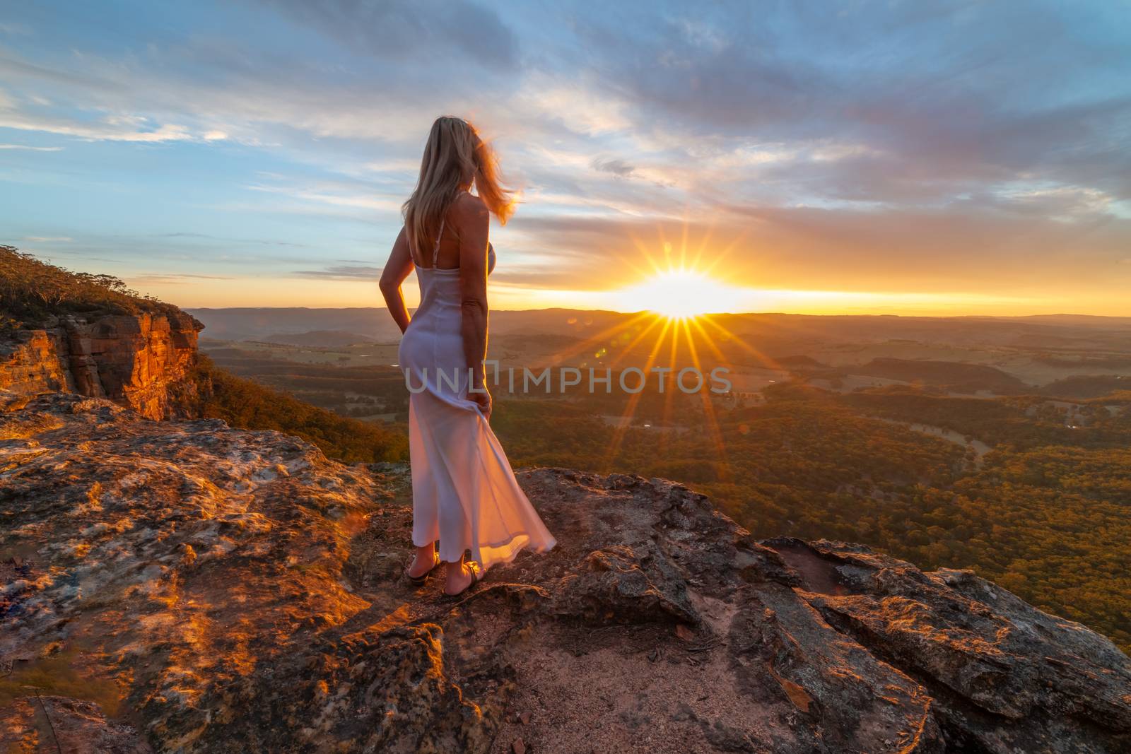 Woman in dress watching blissful sunsets from hidden cliff ledges with spectacular views by lovleah